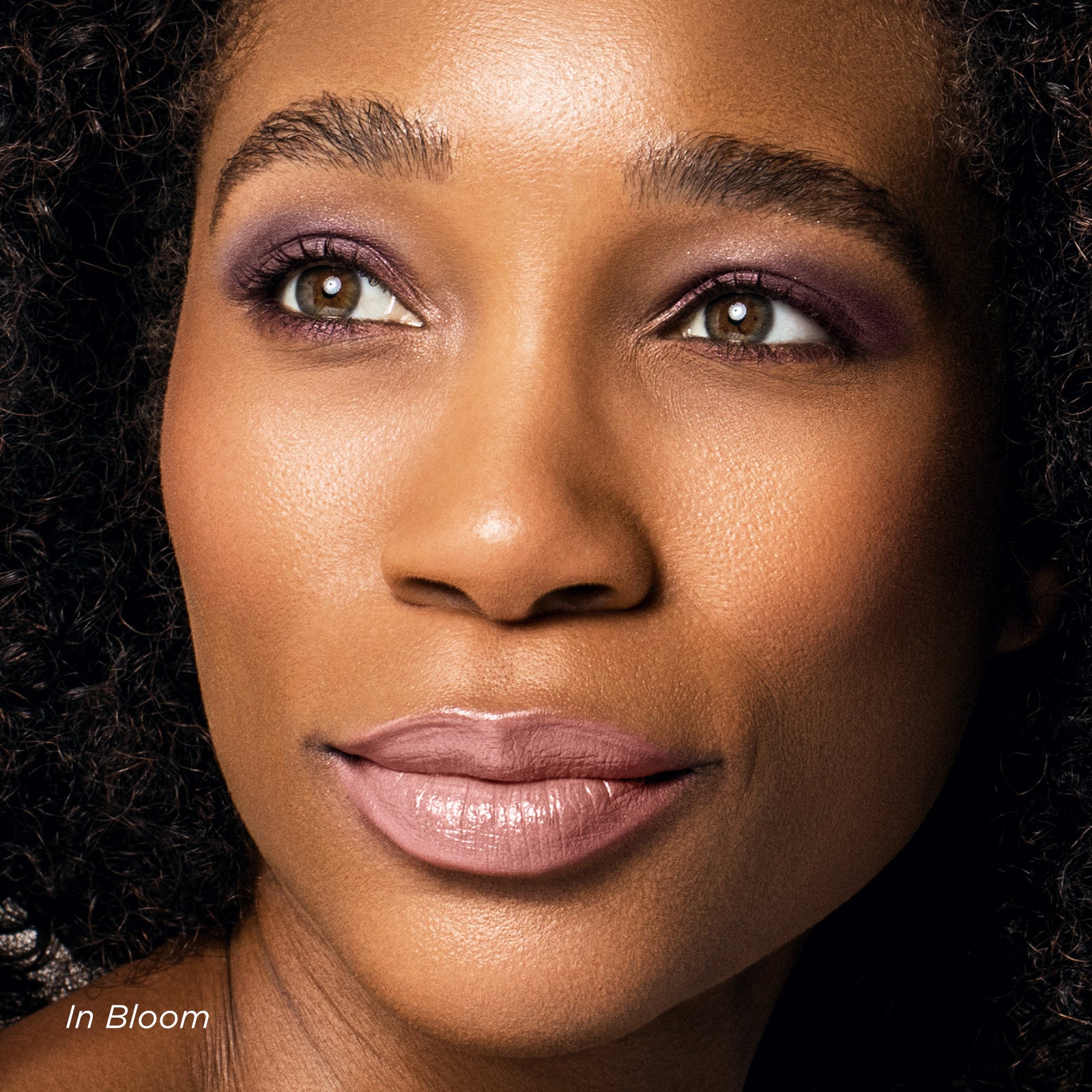 Close-up of a woman's face with makeup, featuring the brand 'In Bloom'.