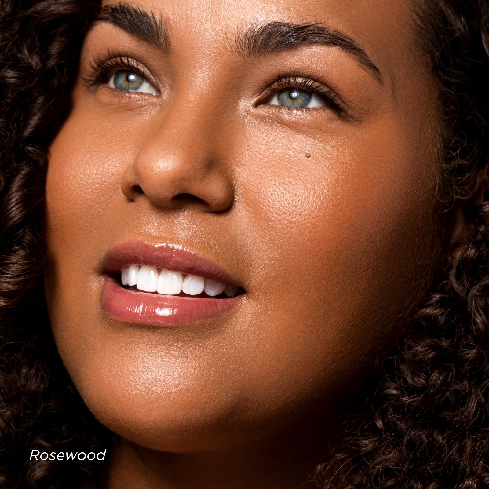 Close-up of a woman's face with a focus on her skin texture, wearing 'Rosewood' makeup.