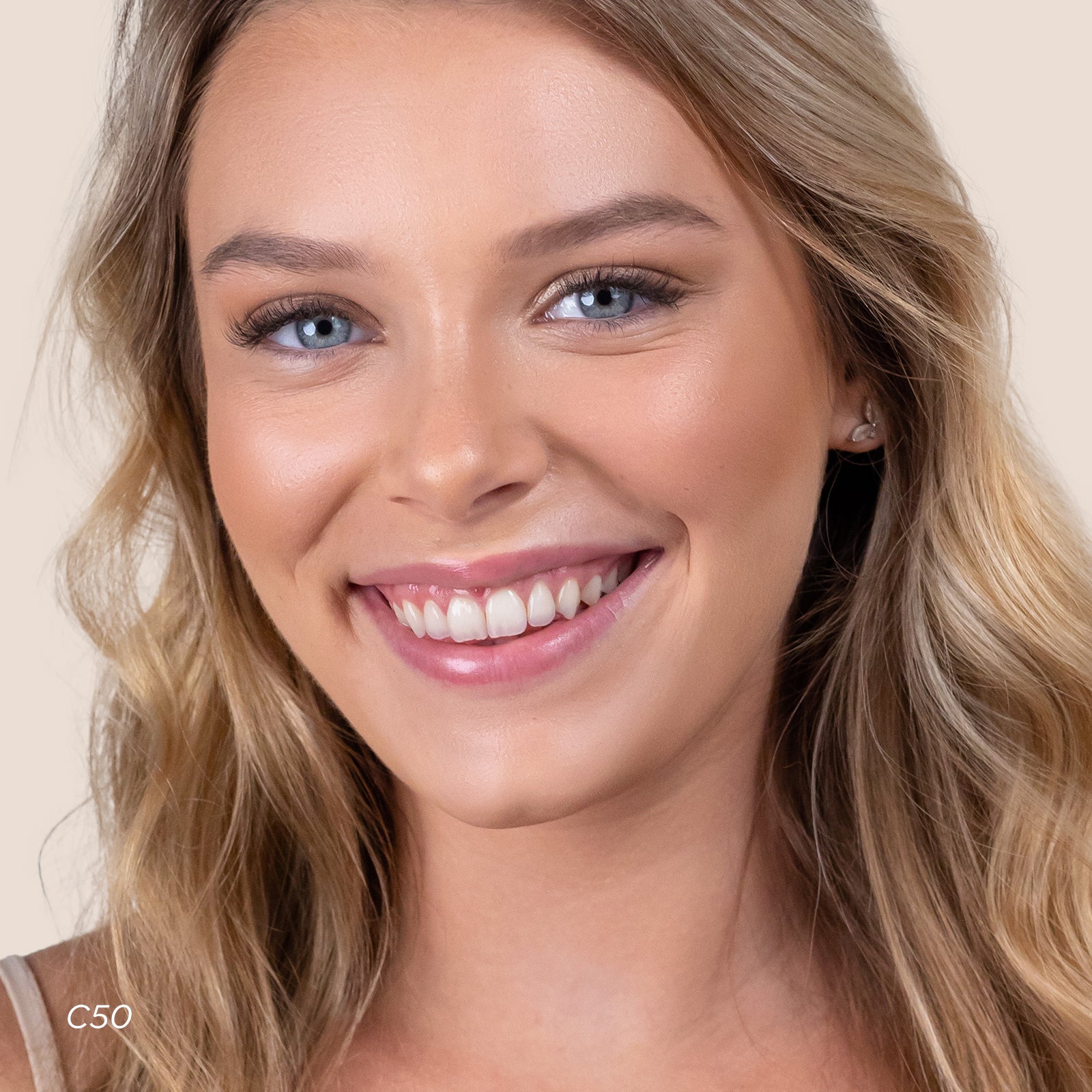 Close-up of a woman with blonde hair and blue eyes smiling.